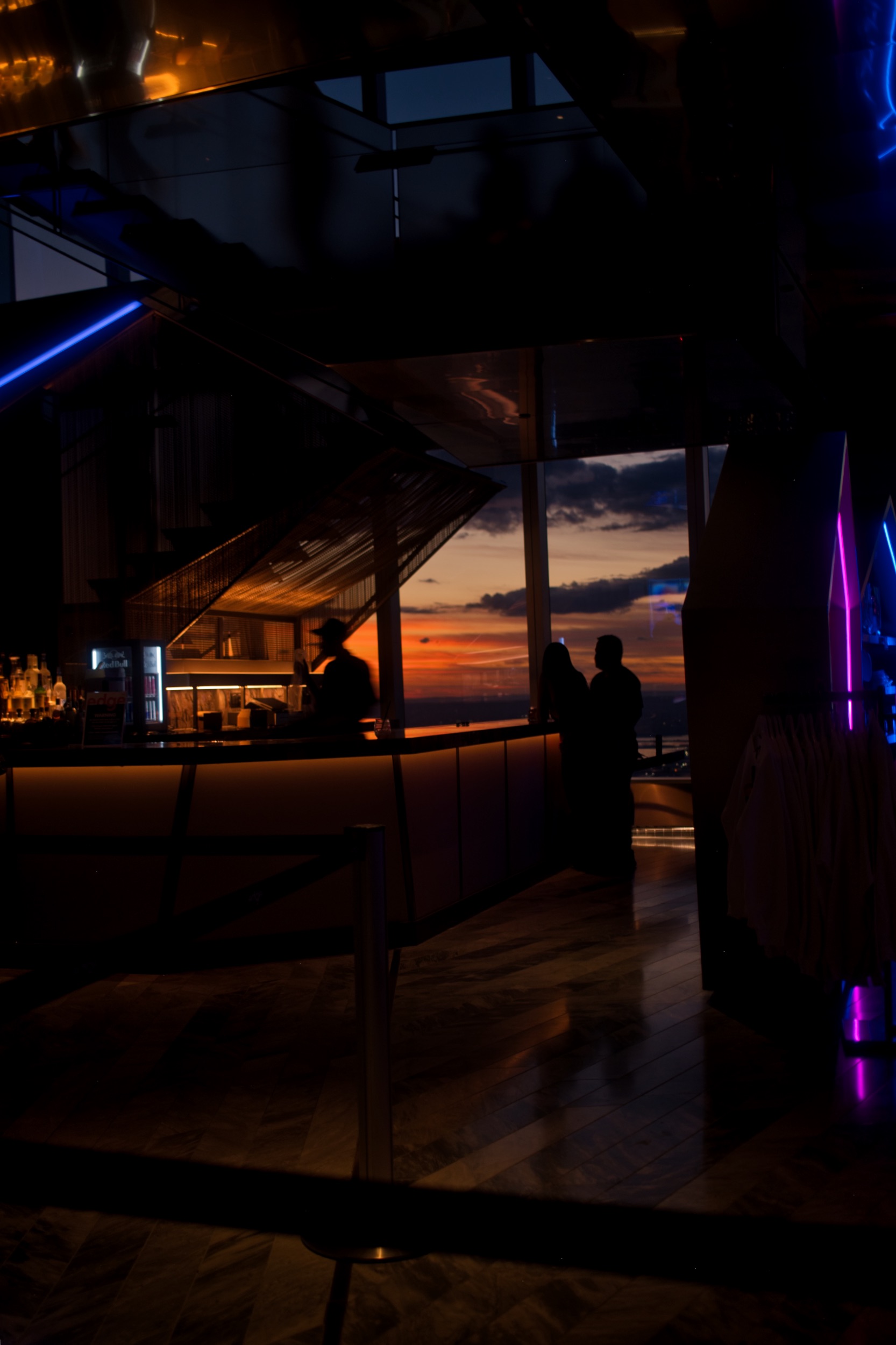 A dark observation lounge lit by purple and orange light